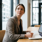 A sharp, natural photograph of a small business owner or marketing professional in a modern workspace, looking thoughtful while reviewing notes about how to communicate the company’s message clearly.